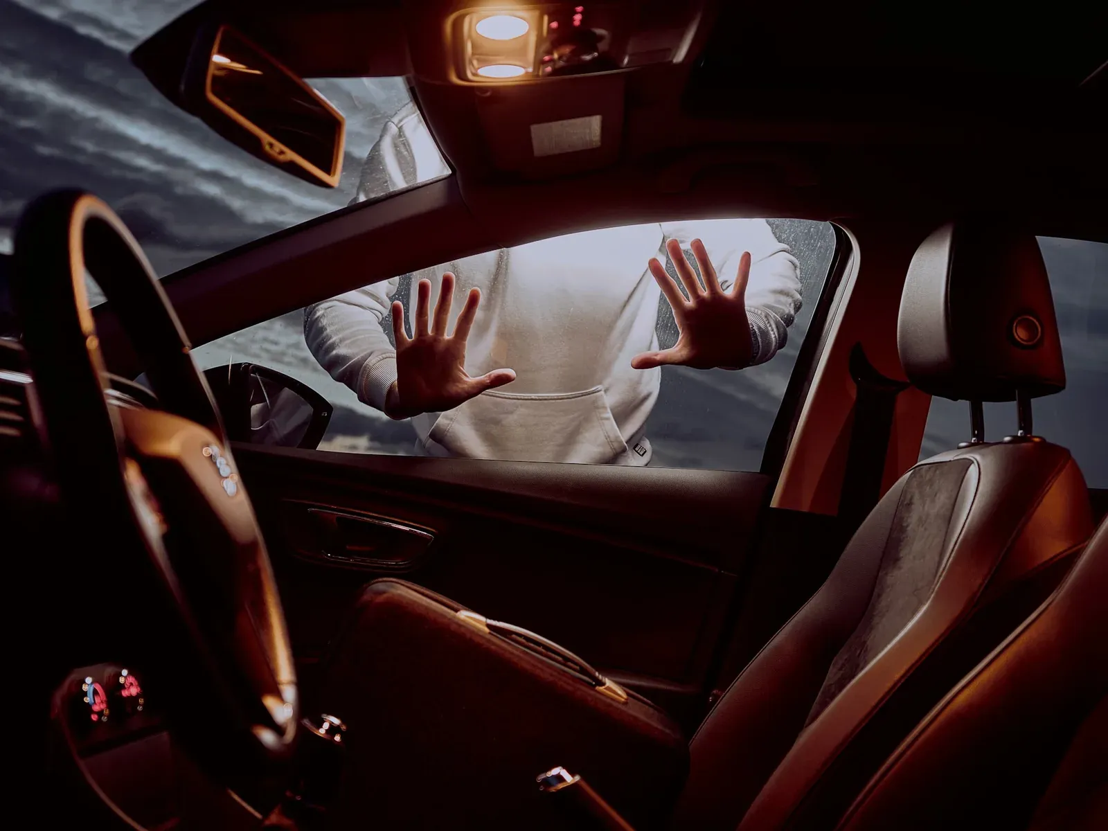 A driver behind the wheel of a modern car, hands on the steering wheel, extending trust to a vehicle increasingly governed by someone else’s software